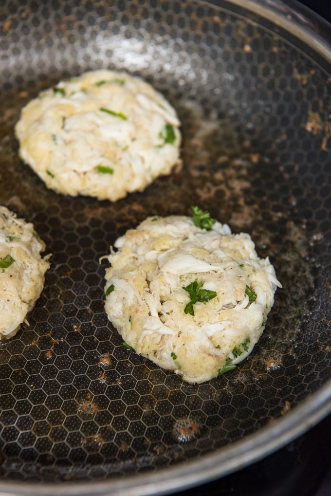 a skillet with crab patties frying.