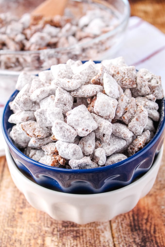 muddy buddies in a small bowl with a bigger bowl and spoon behind