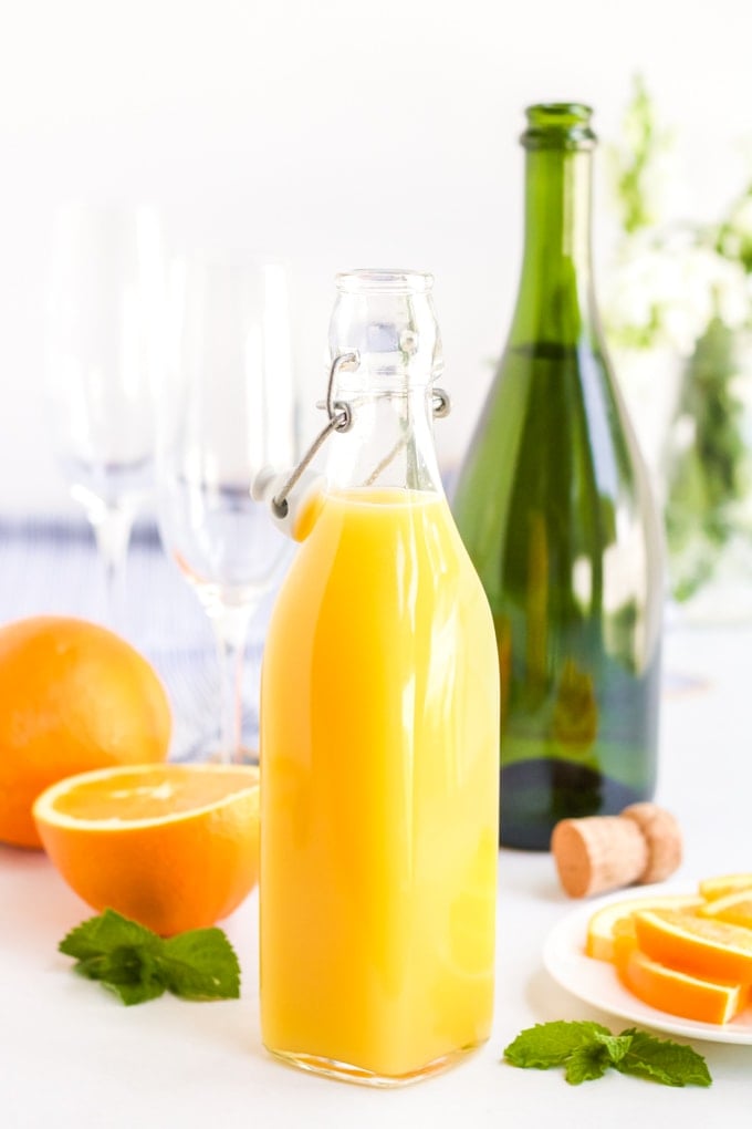 Ingredients for a classic mimosa. Orange juice, oranges and sparkling wine. 