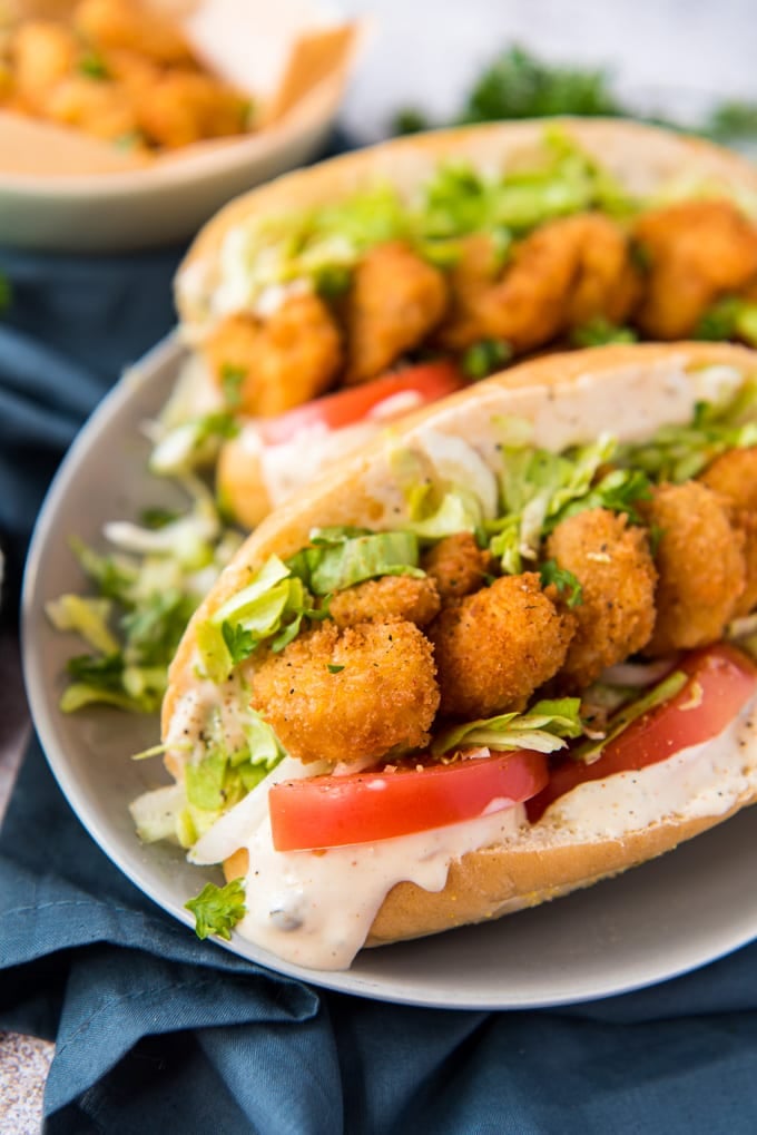 a white platter with shrimp po boy sandwiches