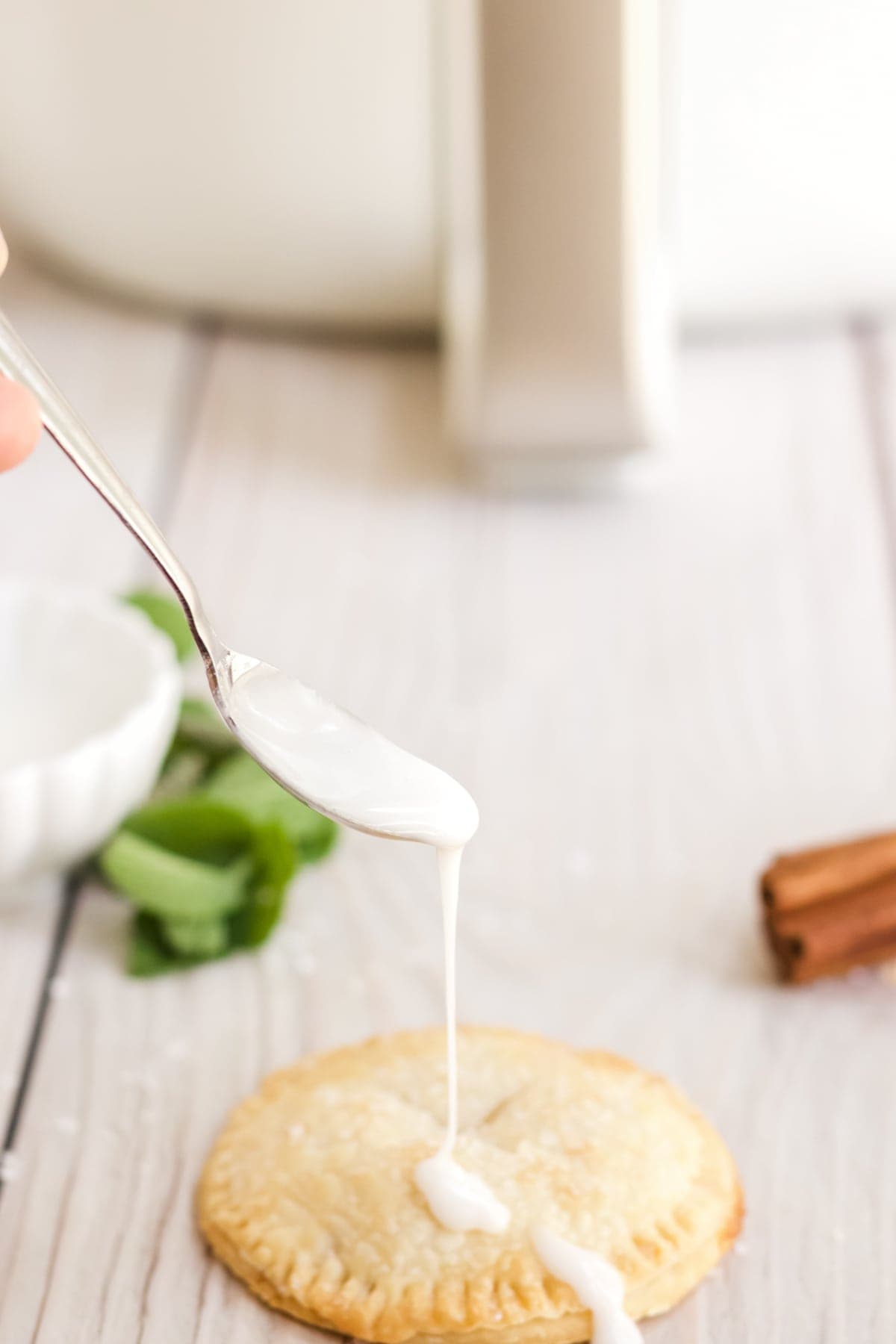 Glaze being drizzled on the top of apple hand pies