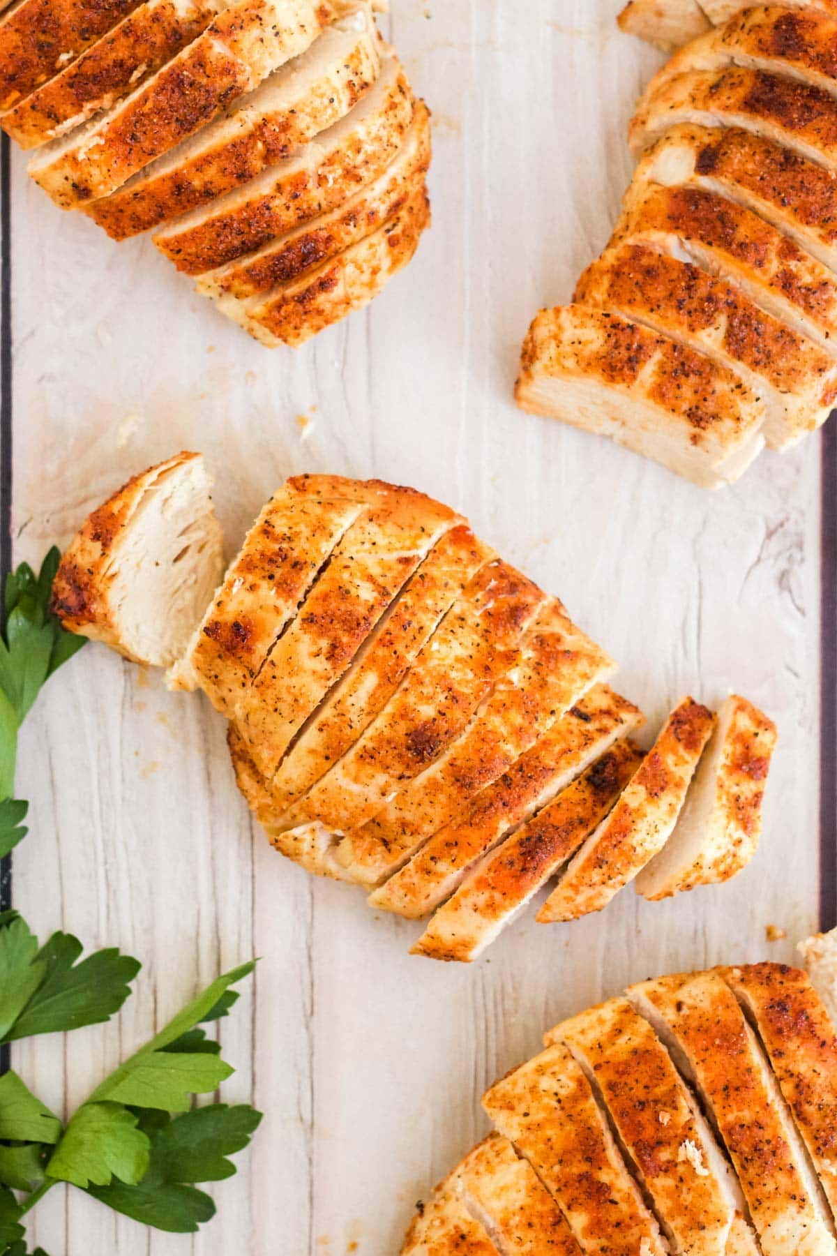 chicken breasts, sliced, on a white wood background, parsley