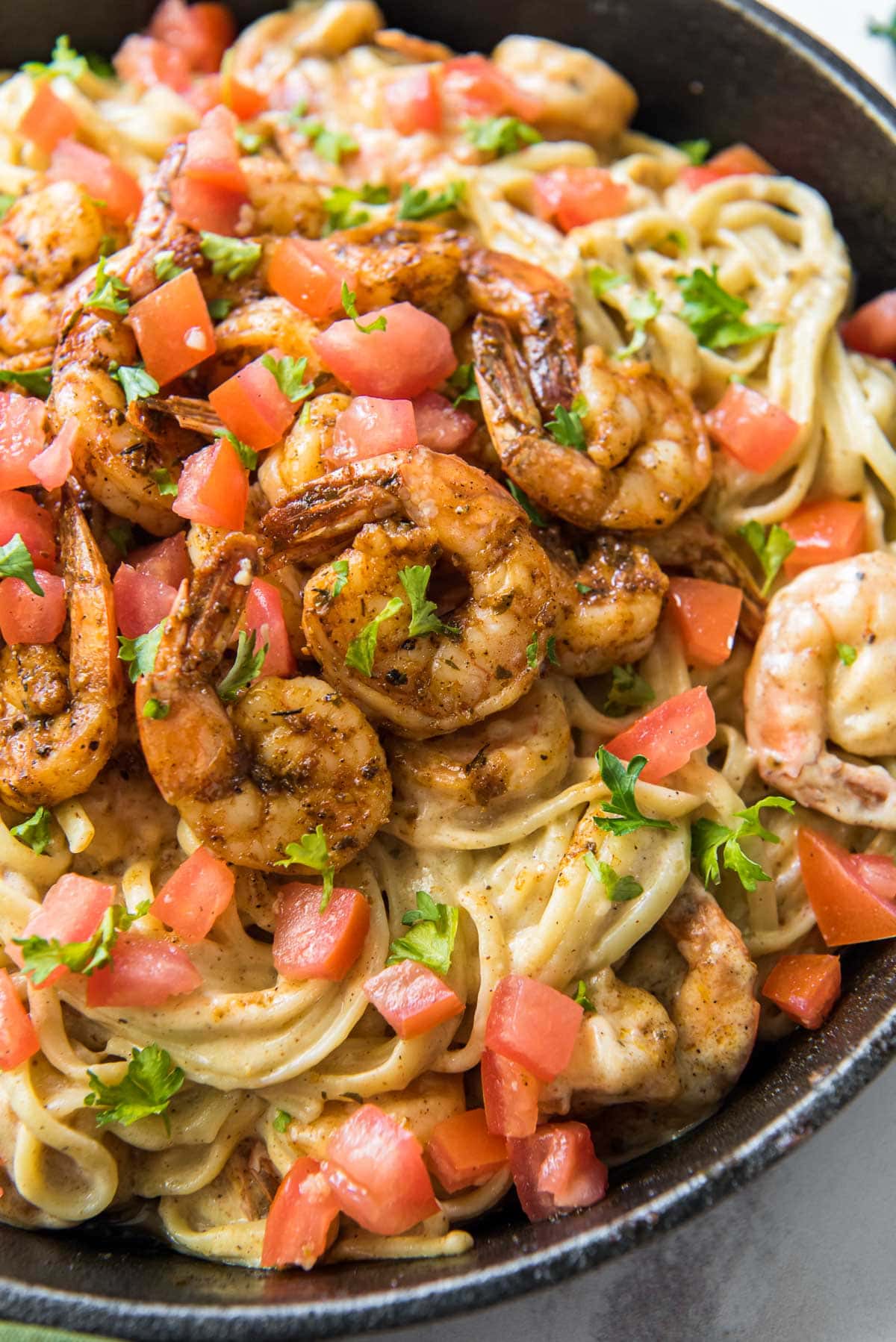 cajun shrimp pasta with diced tomatoes in a cast iron skillet