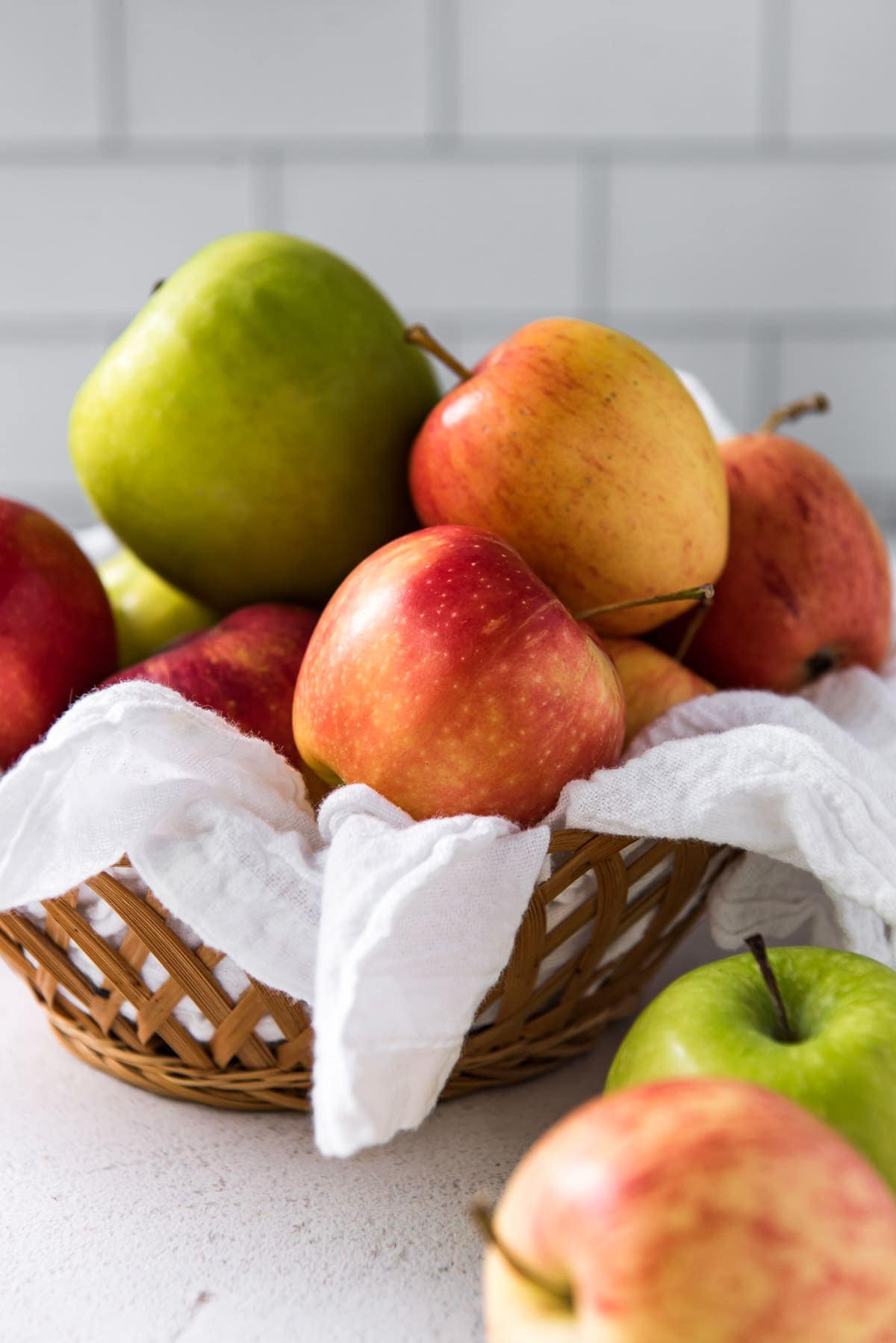 basket with white napkin, green and red apples