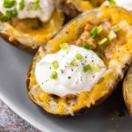 a potato skin with cheese, bacon, sour cream and chives