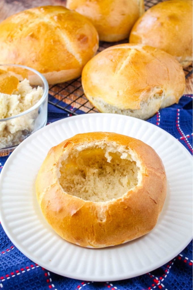 bread bowl on a plate with more bread on a wire rack behind it