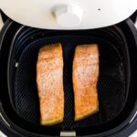 Two pieces of cooked salmon in an air fryer tray