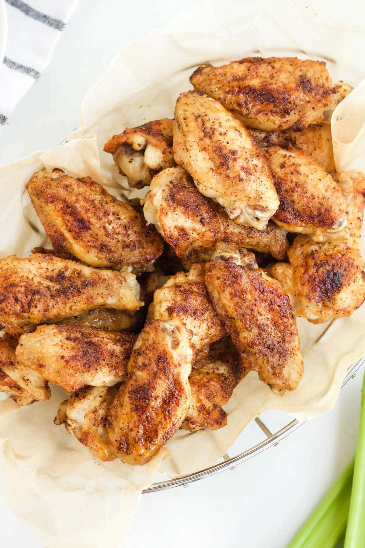 chicken wings in a basket, white background, some celery