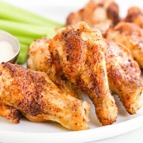 crispy chicken wings, celery and ranch on a white plate