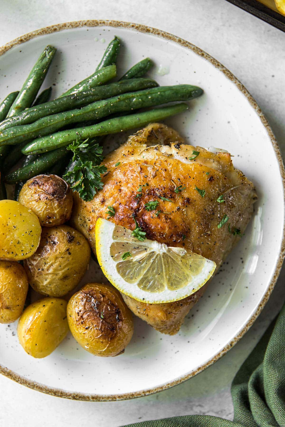 white plate, chicken thigh, potatoes, green beans