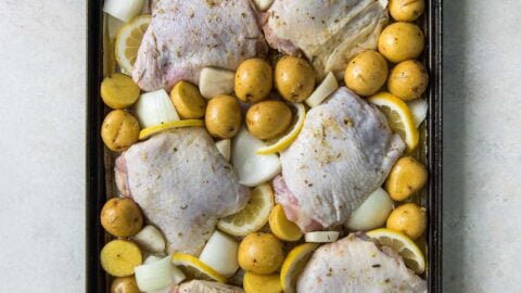 raw chicken thighs with skin, potatoes, onions and lemon slices