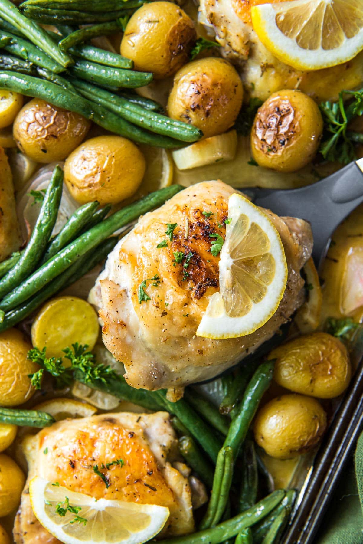 chicken and potatoes and green beans and lemon slices on a sheet pan