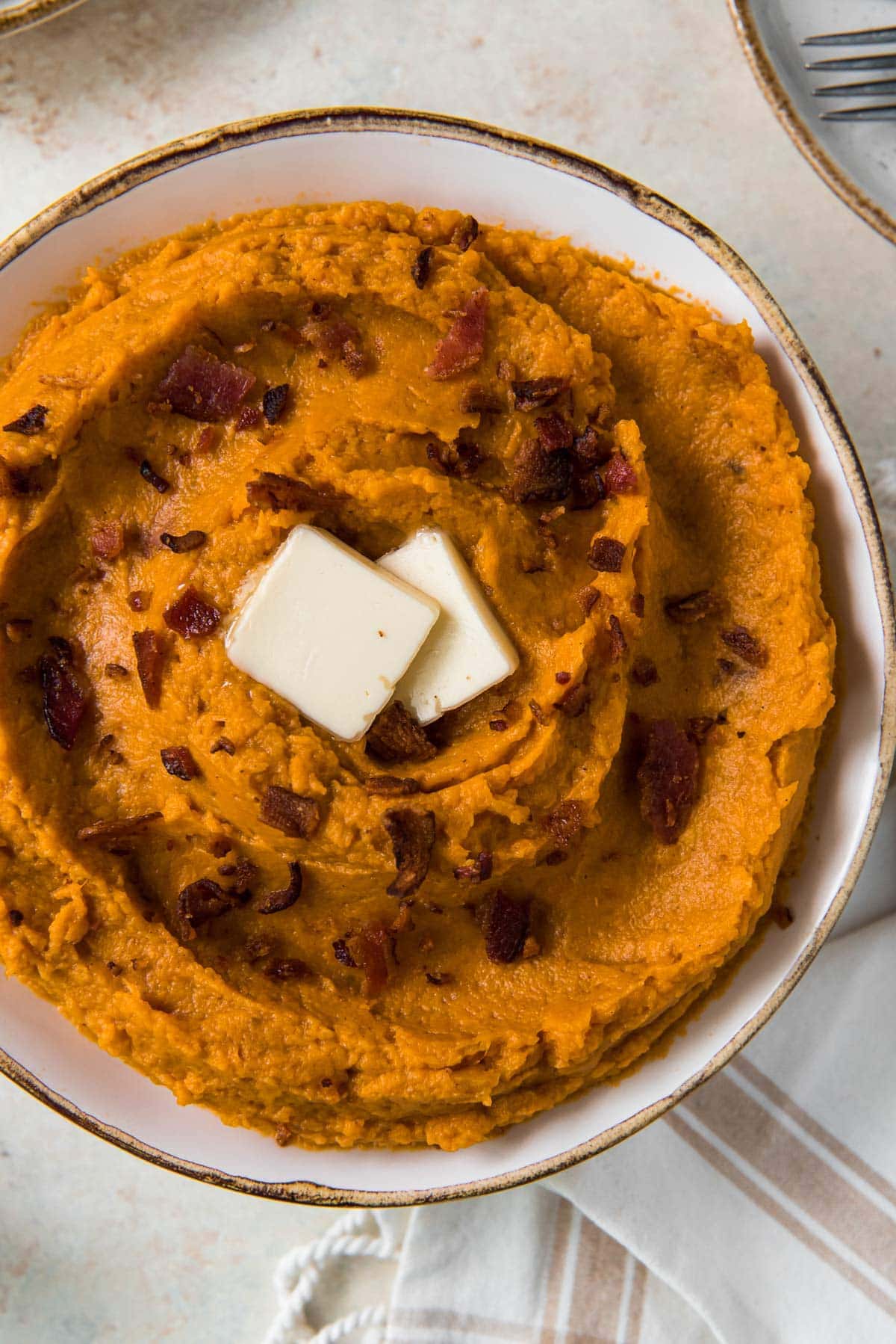 mashed sweet potatoes, white bowl, bacon, butter
