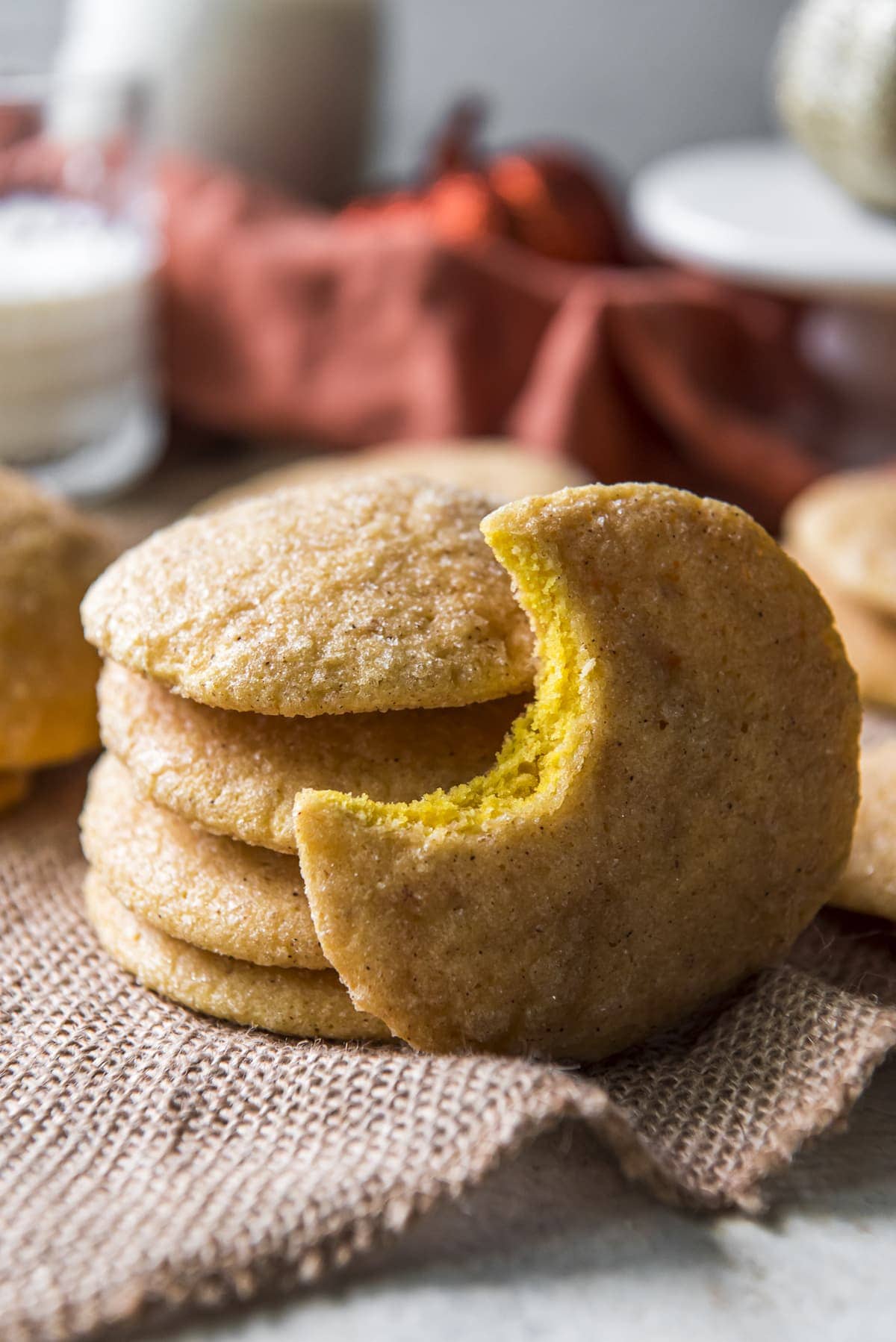 stack of cookies, a cookie with a bite out of it, orange napkin, burlap