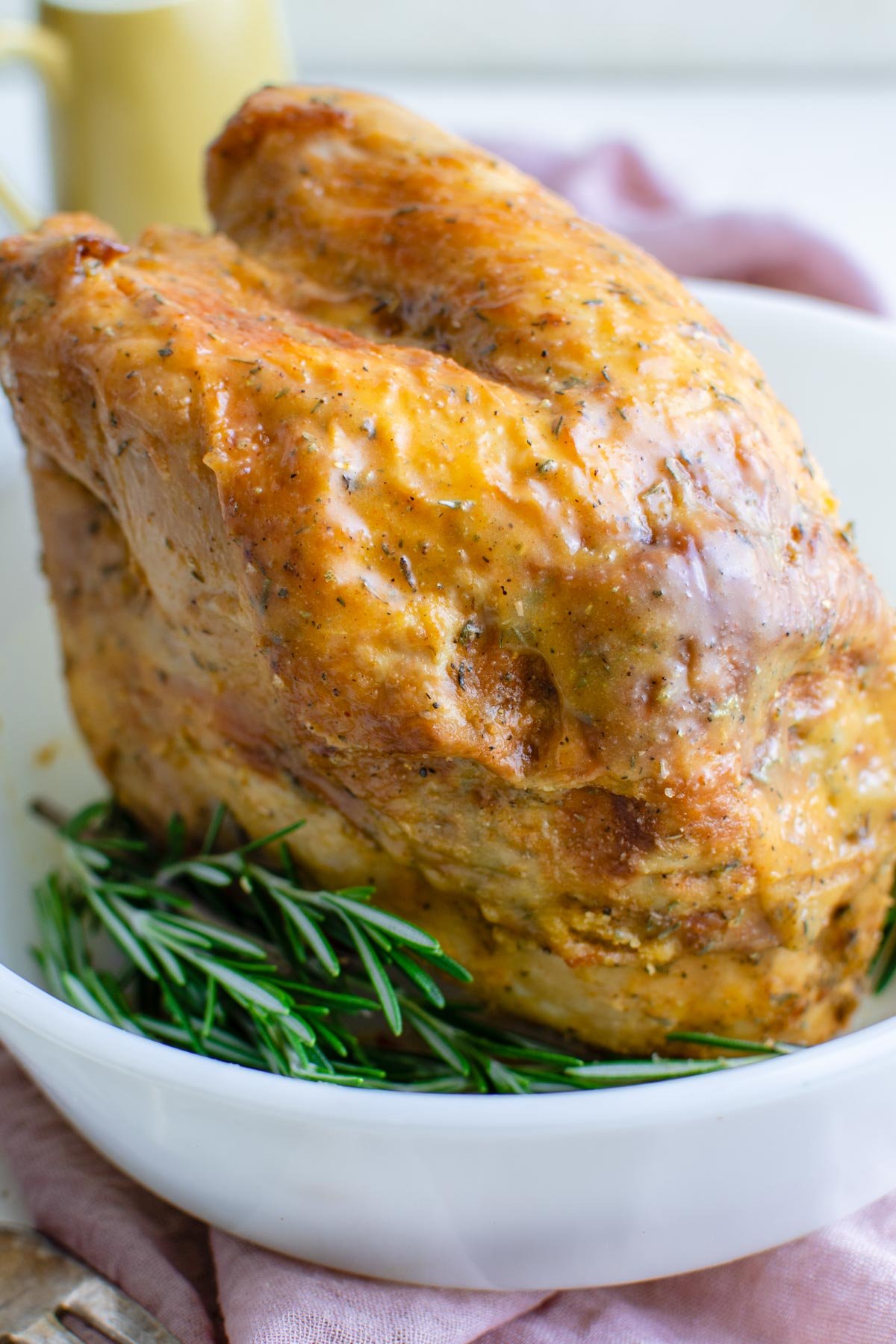 a whole turkey breast with crispy skin, a white dish, green leaves