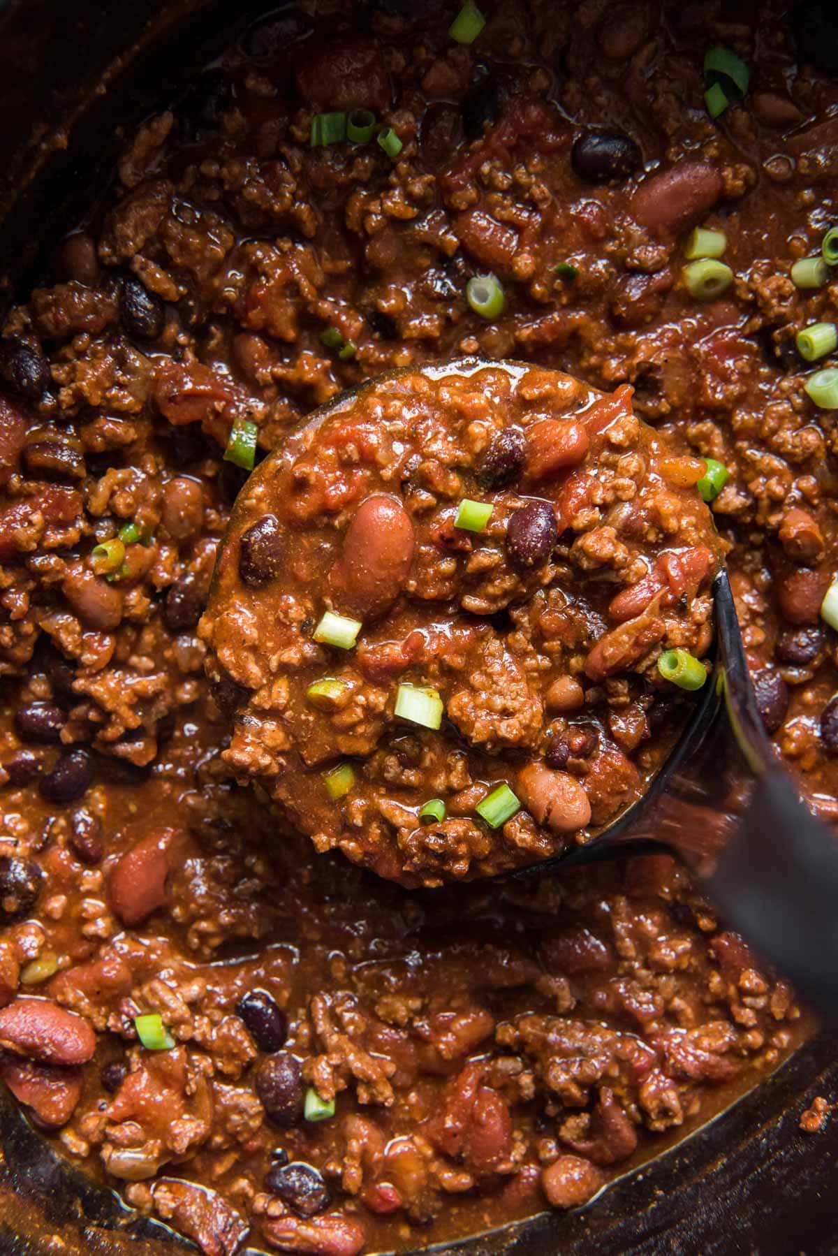 beef chili in a slow cooker pot, ladle