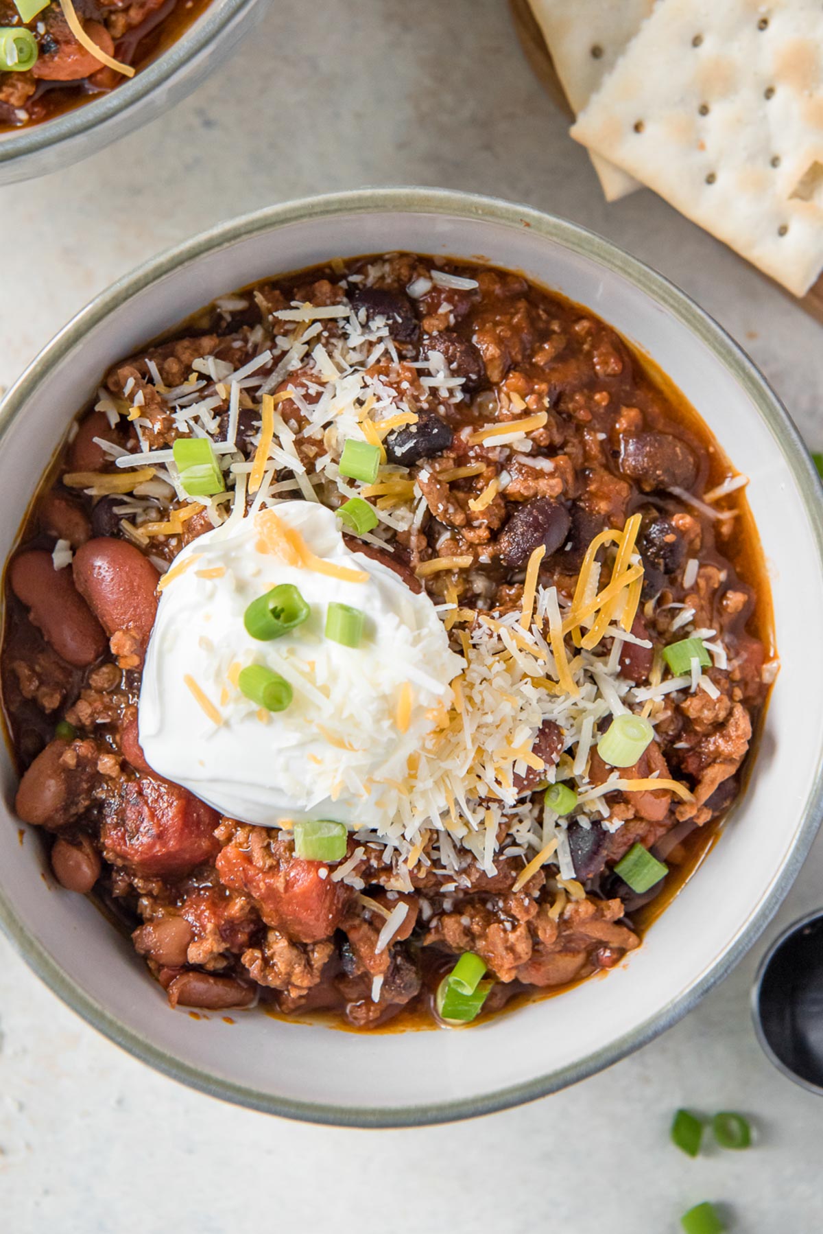 close up bowl of chili with sour cream and cheese