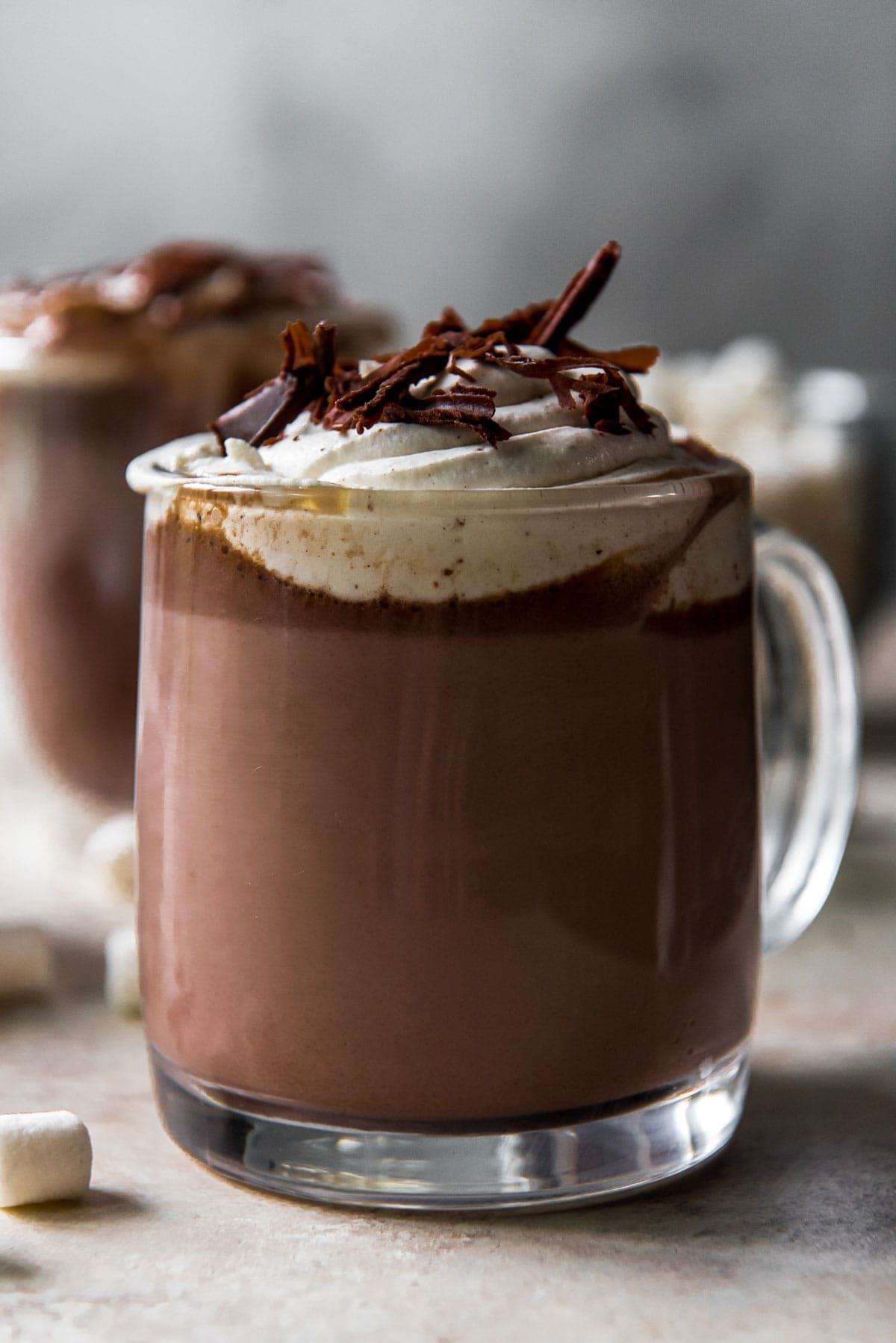hot chocolate in clear glasses, whipped cream, chocolate shavings, marshmallows