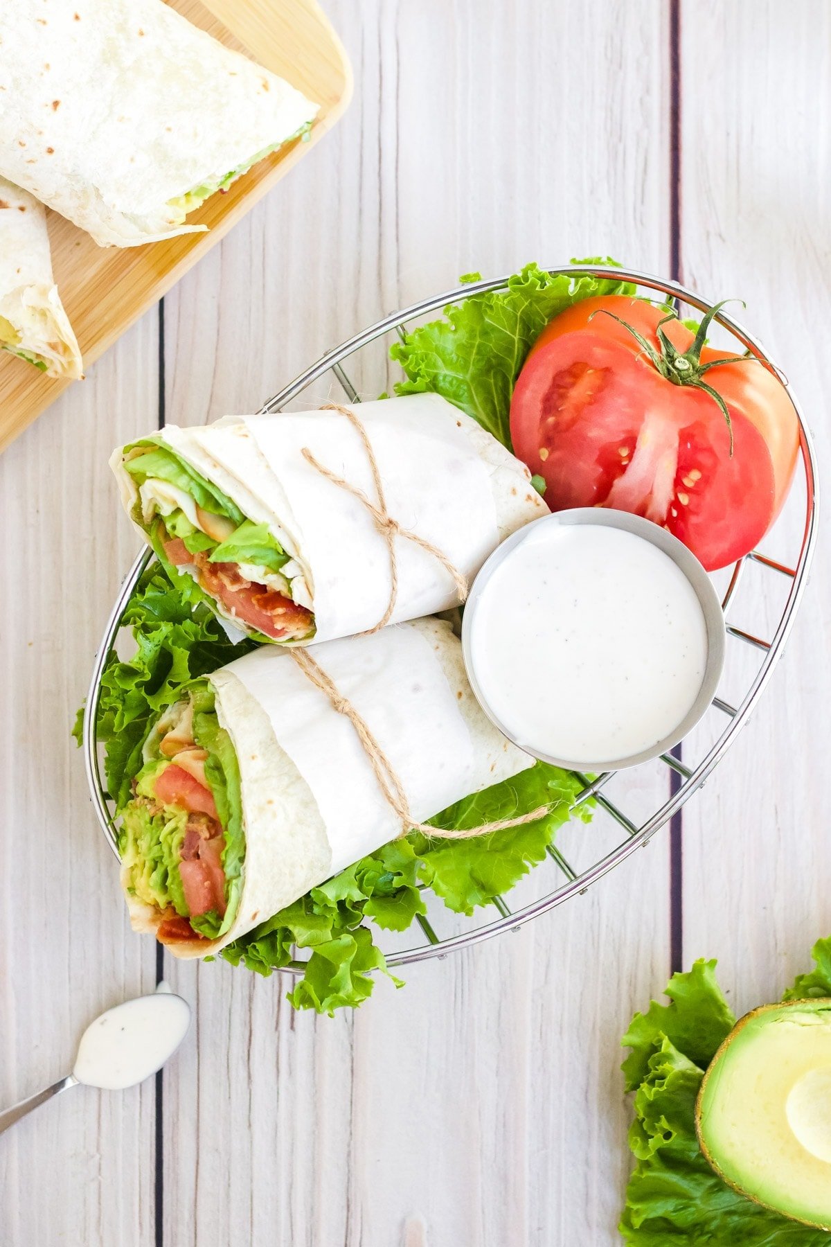 Two turkey BLT halves wrapped in parchment and served in a basket