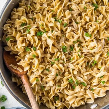 egg noodles with butter, wooden spoon, silver pan