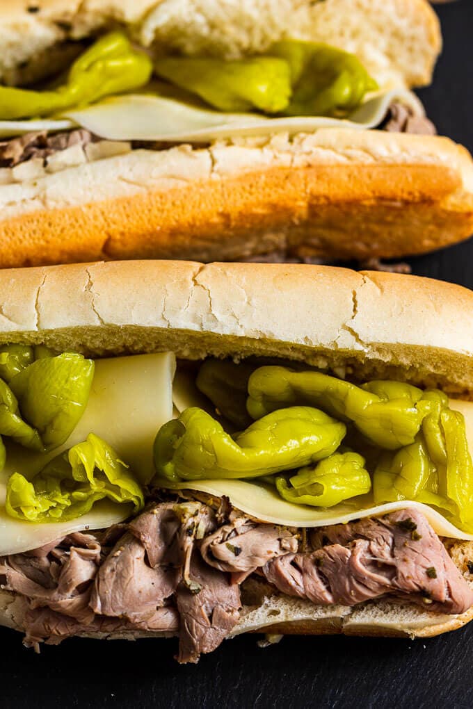 Two Italian beef sandwiches on slate tile.