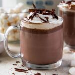 hot chocolate in a clear glass, whipped cream, chocolate shavings, marshmallows