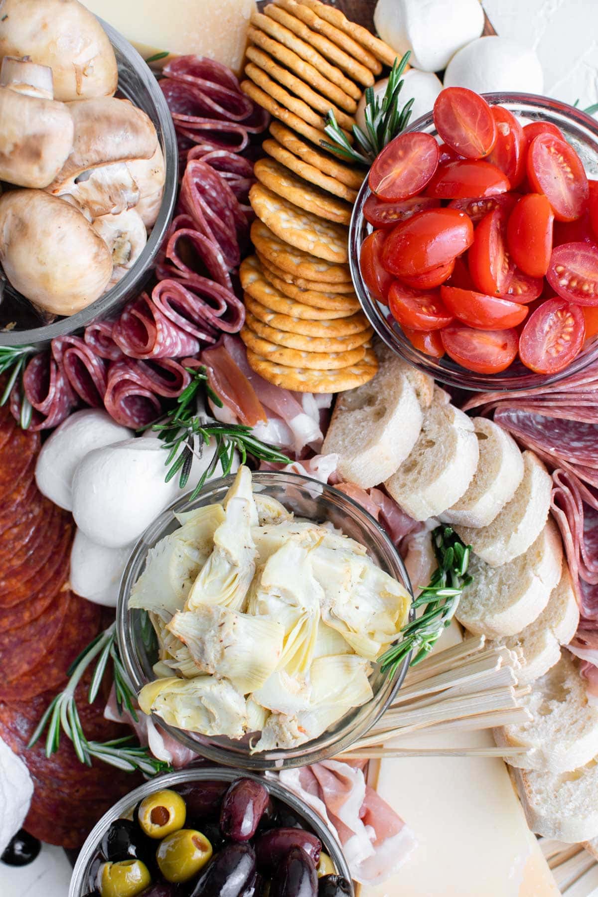 antipasto platter with meat, cheese, crackers, tomatoes, mushrooms, olives, artichokes