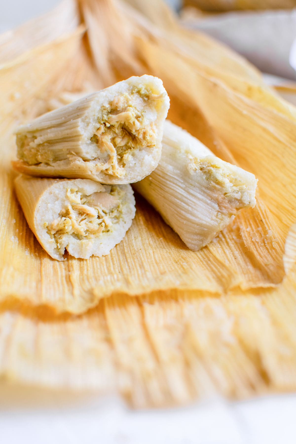 chicken tamales cut open and sitting on corn husks