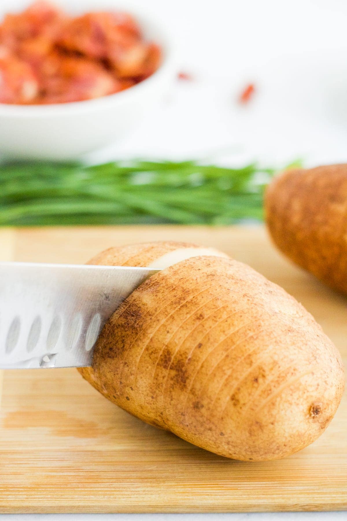 A russet potato being sliced to make Hasselback Potatoes