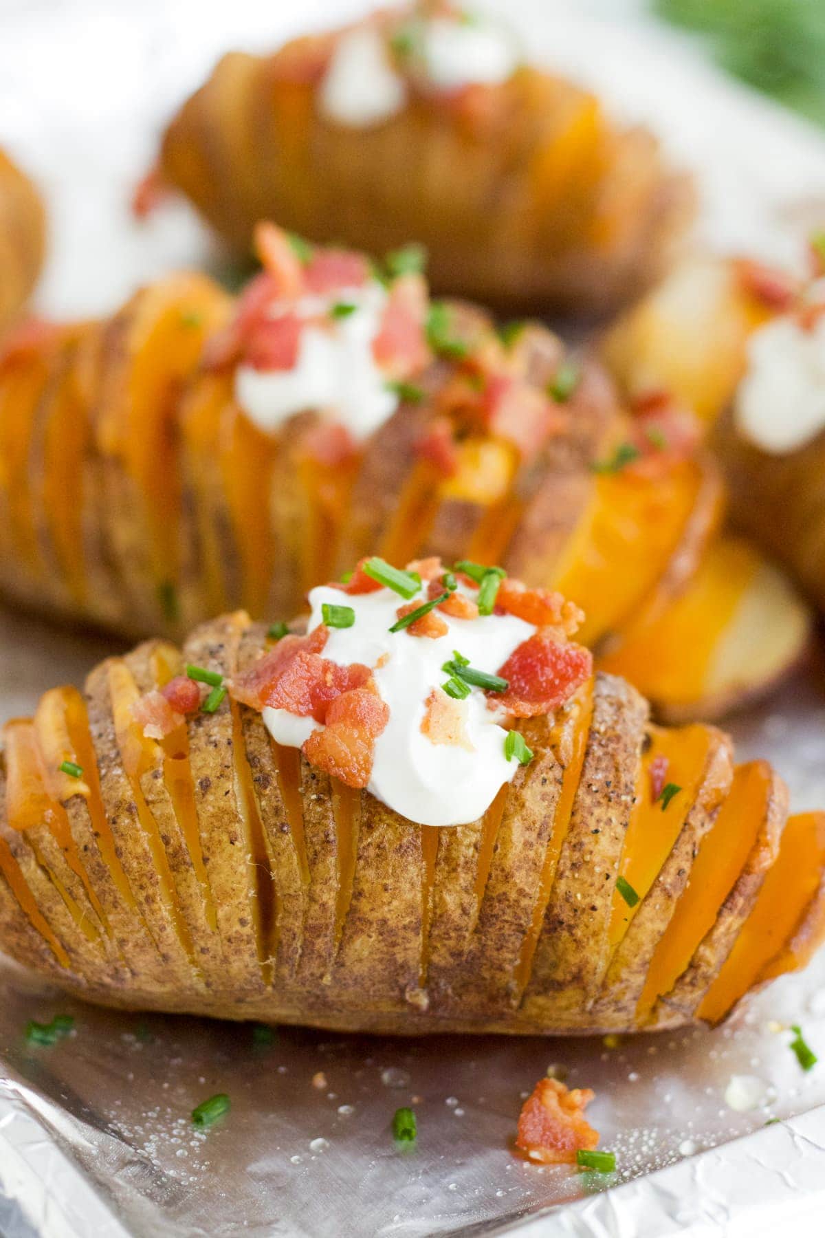 Hasselback potatoes on a baking sheet with fully loaded toppings