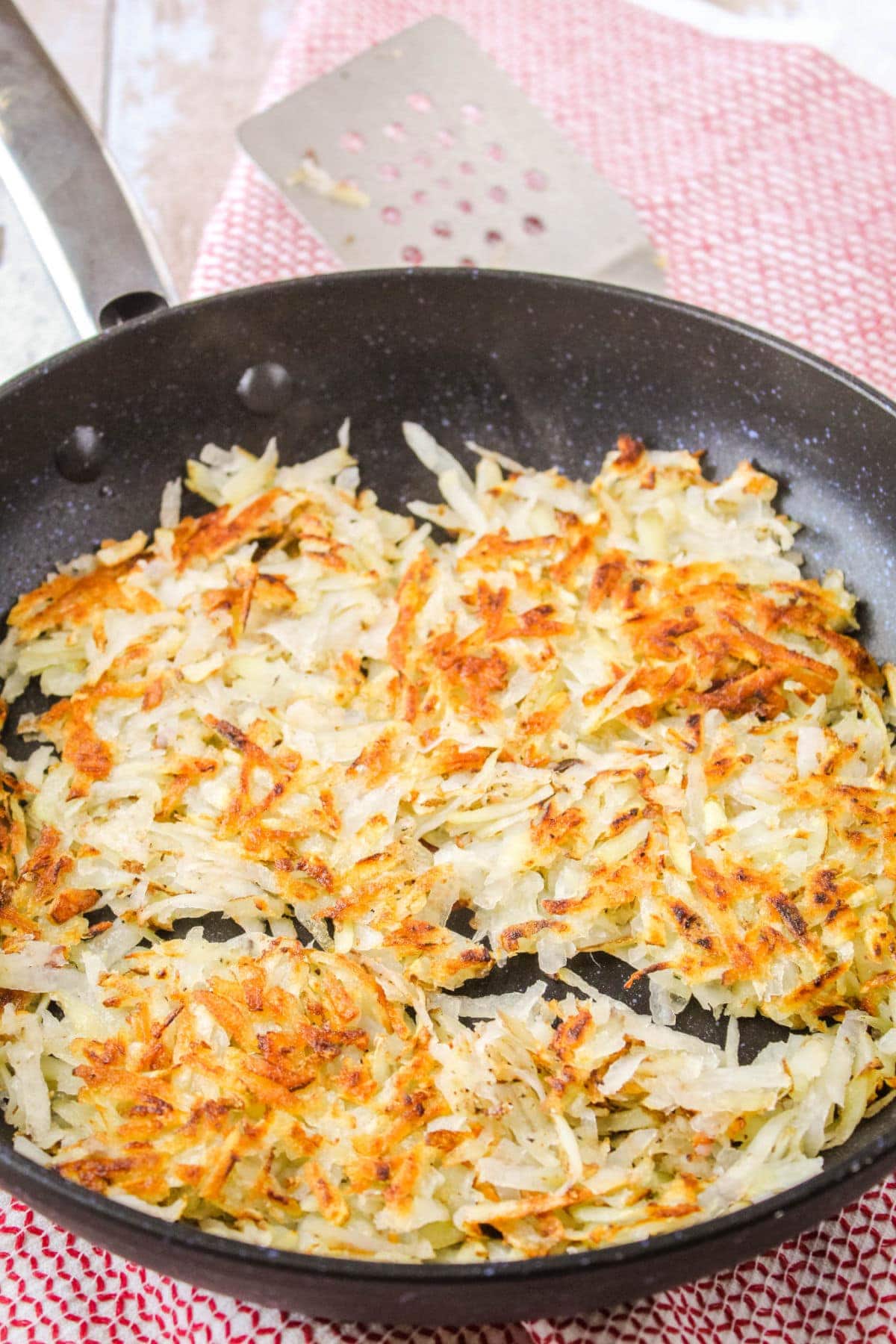 My Homemade Hash Browns Recipe will have your craving potatoes with your breakfast! Easy to make and such a simple recipe! crispy hash browns in a skillet next to a spatula