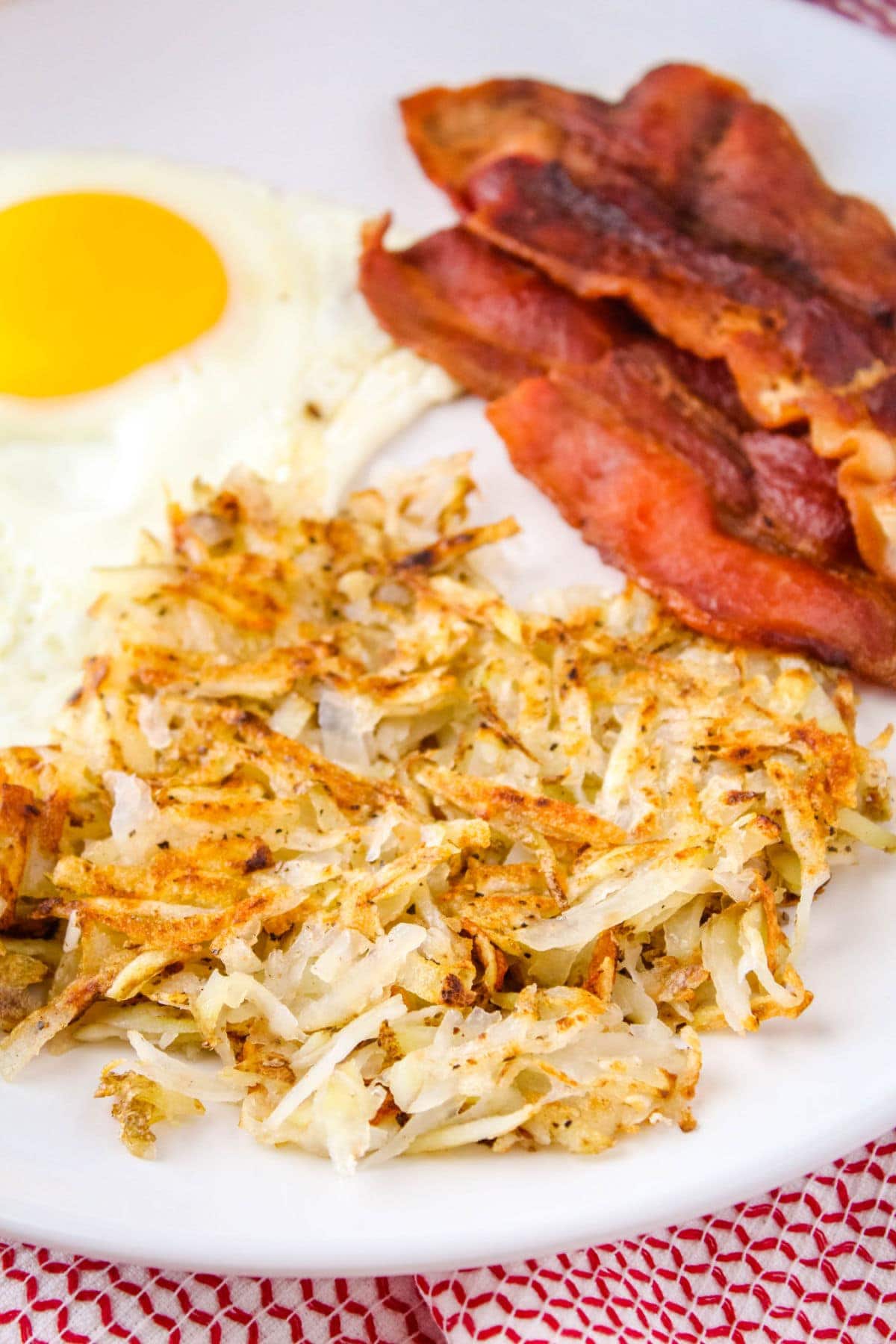 hash browns served on a palte with bacon and sunny side up eggs