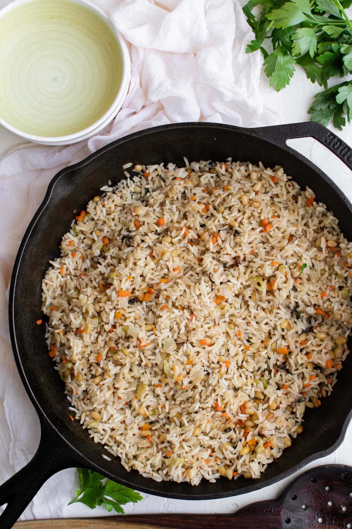 cast iron skillet with rice pilaf, plates, parsley