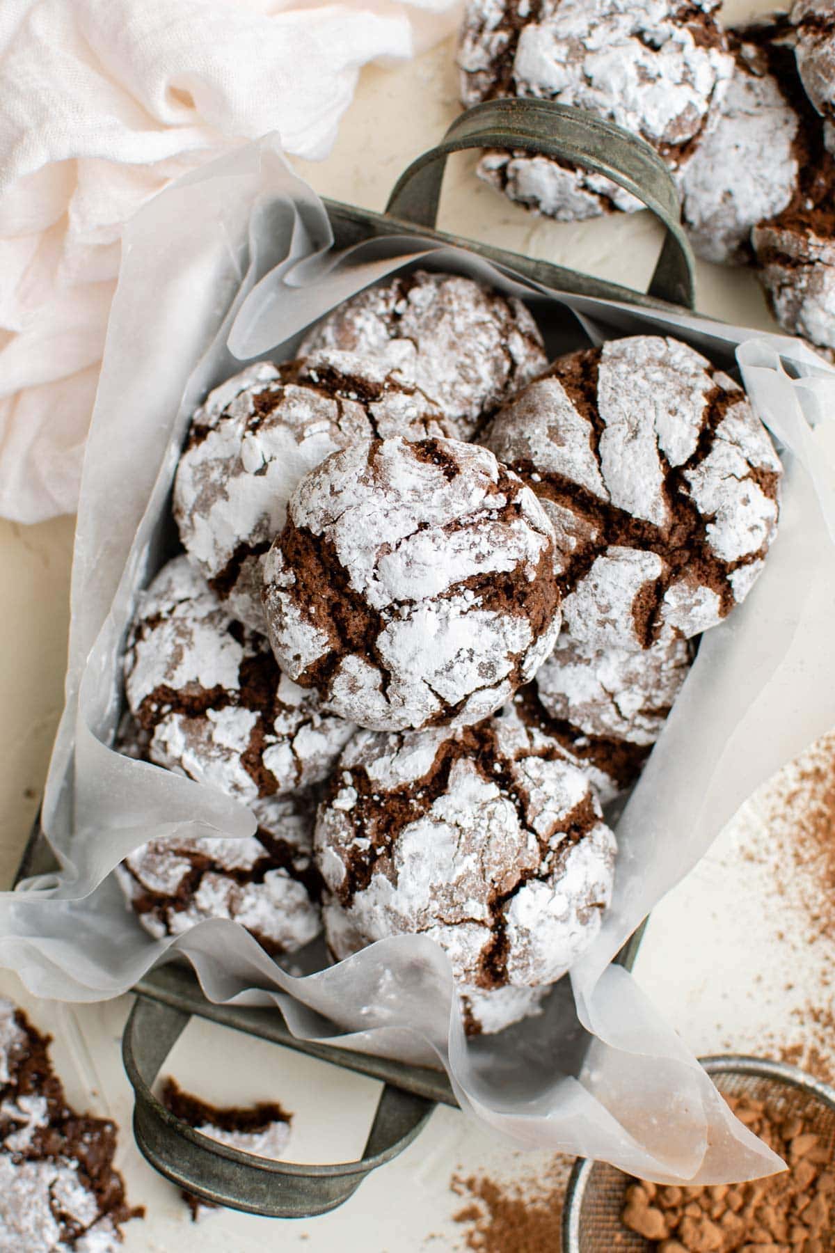 overhead shot of chocolate crinkle cookies in a box with parchment paper