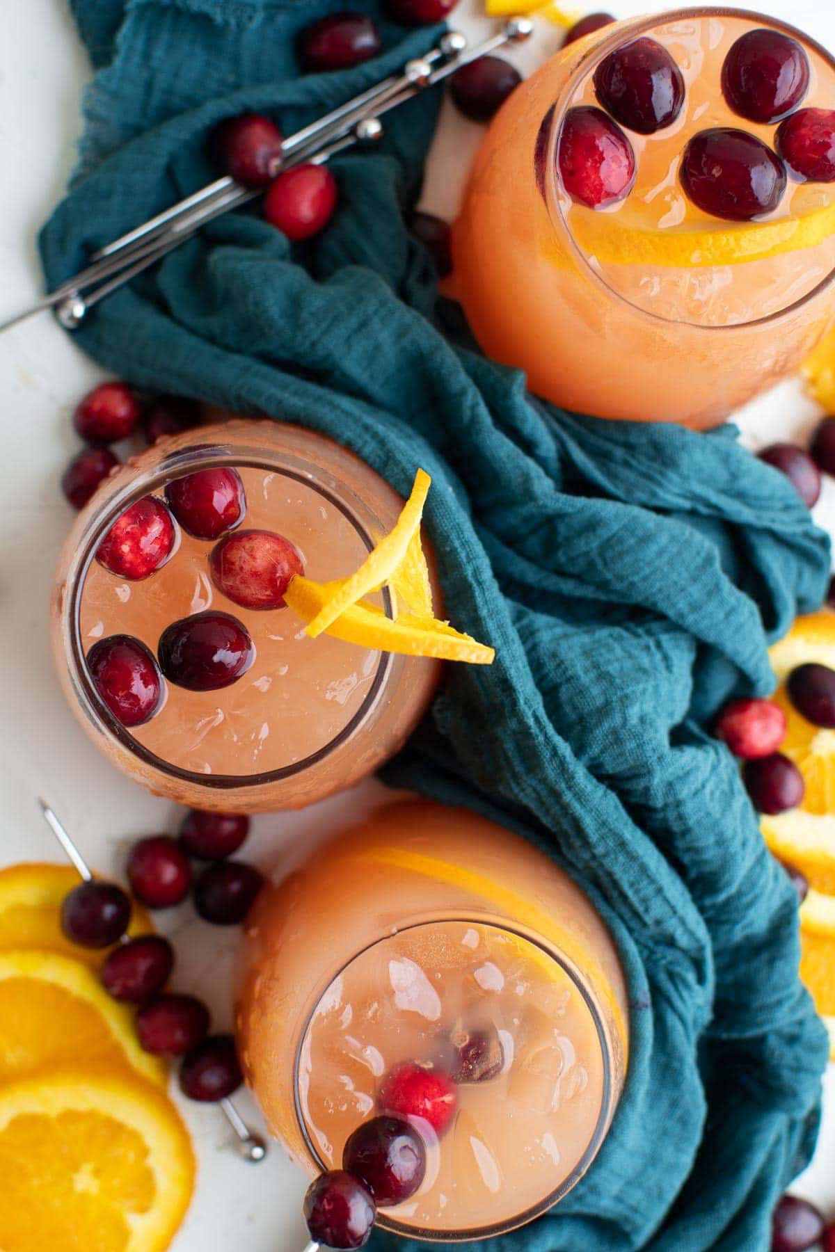 glasses of christmas punch, cranberries, orange slices, blue napkin