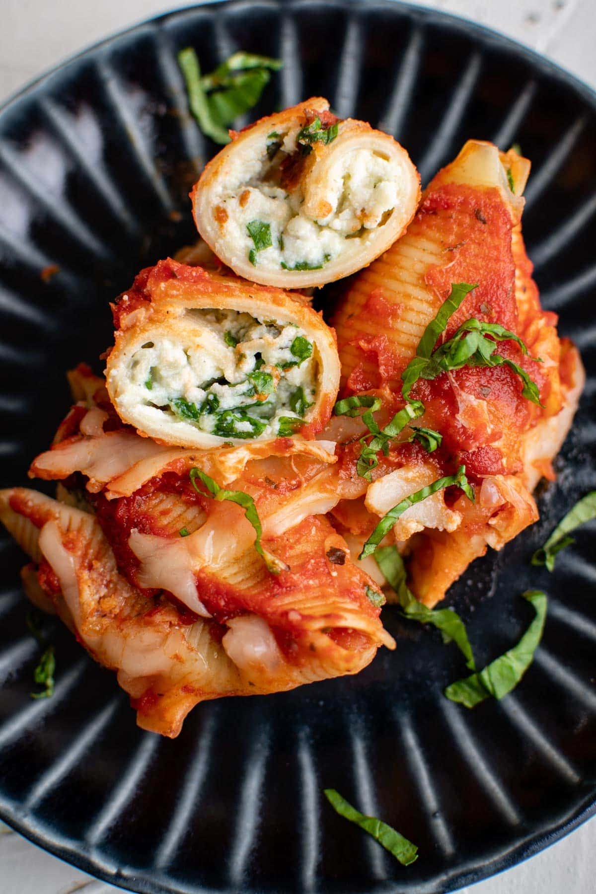 stuffed shells, spinach, basil, red sauce, cheese, black plate