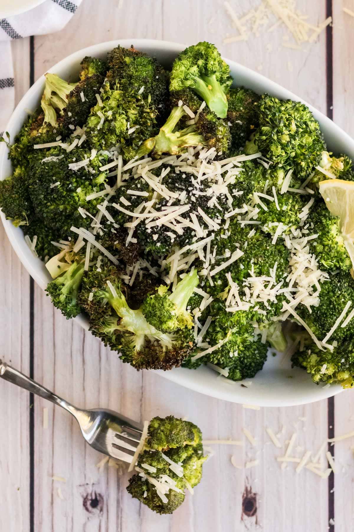 broccoli, white casserole dish, fork, parmesan cheese, lemon