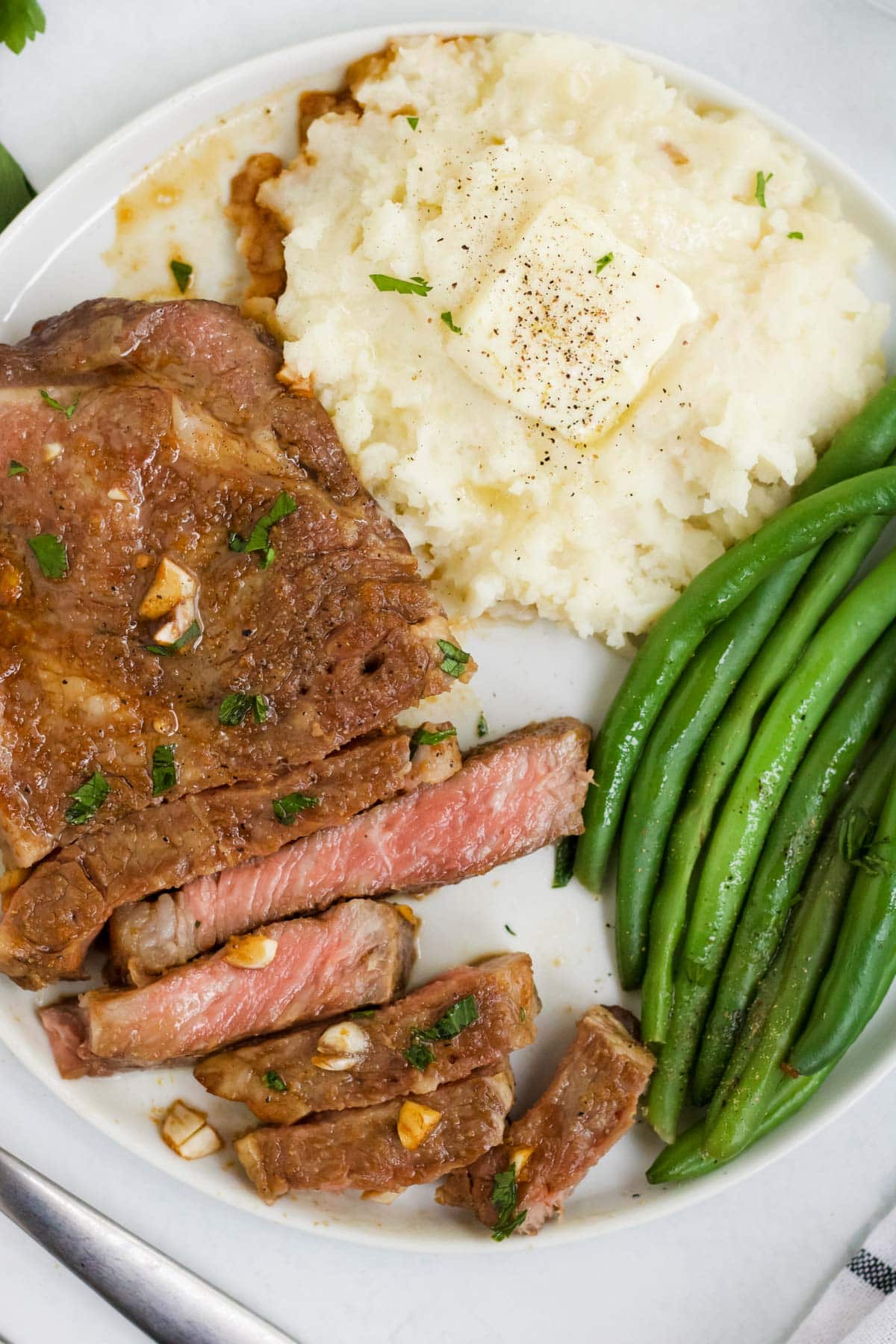 white plate, steak, green beans, mashed potatoes