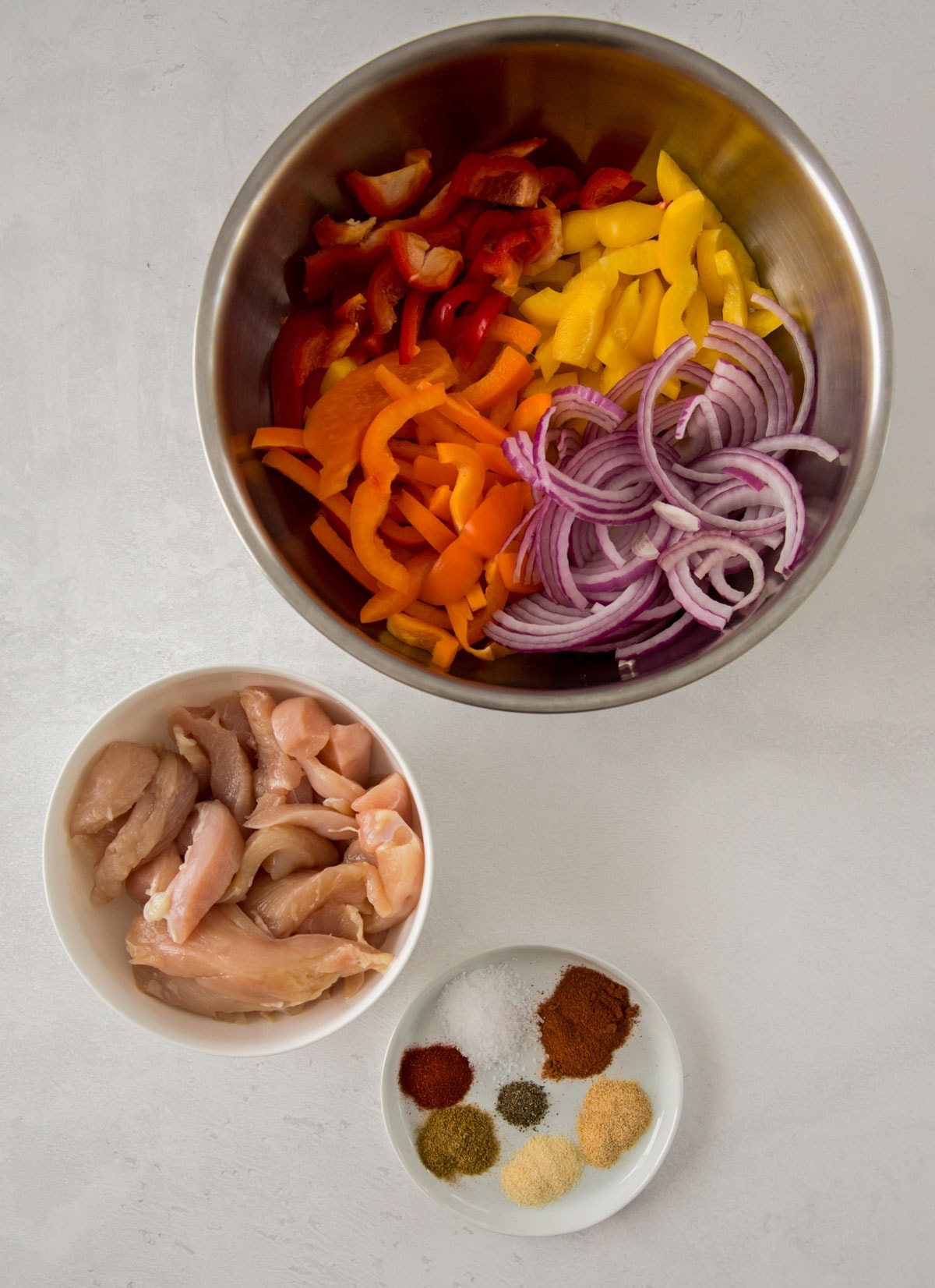 small bowls with onions, bell peppers, chicken and seasonings