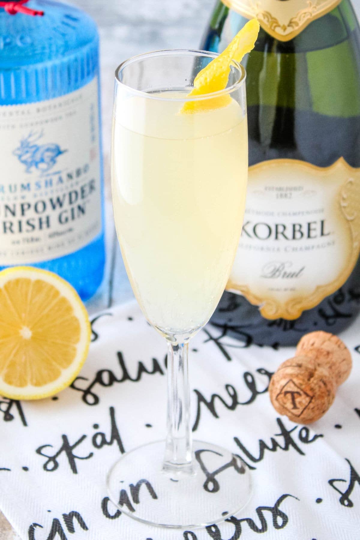 close up of a french 75 in front of gin and champagne bottles