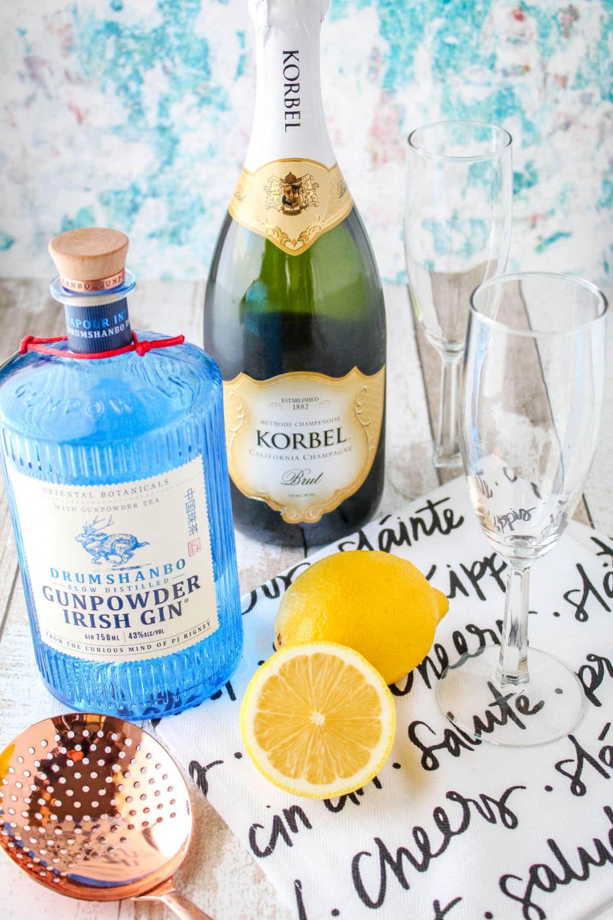 ingredients to make a French 75 cocktail next to champagne flutes