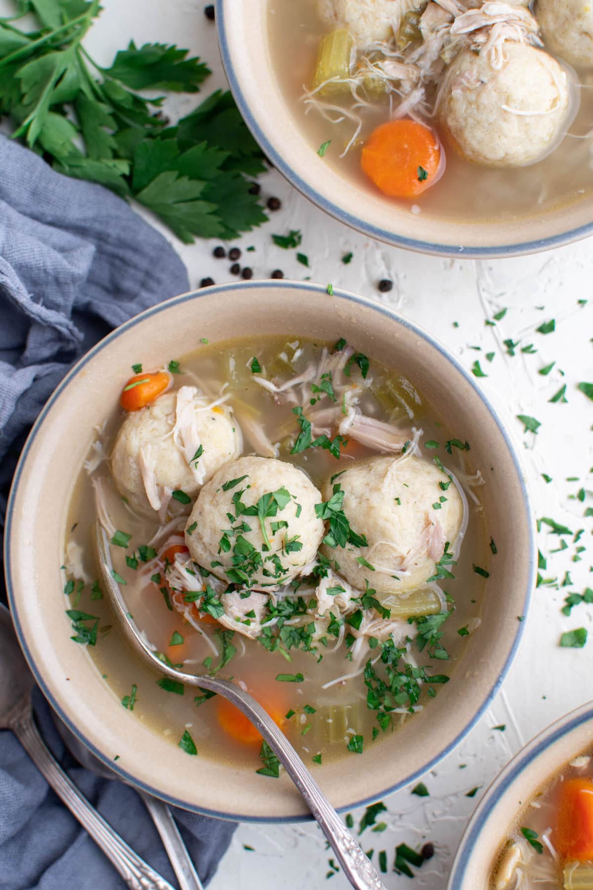 bowls of matzo ball soup, blue napkins, parsley