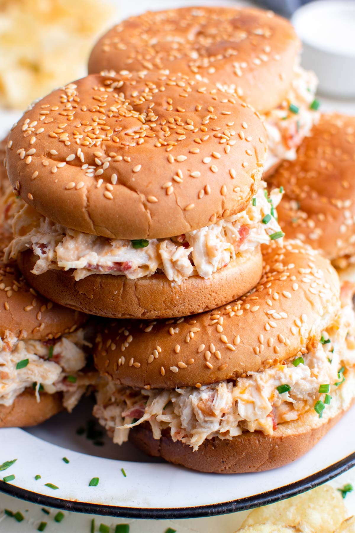 shredded chicken sandwiches with sesame seed buns, white plate, potato chips