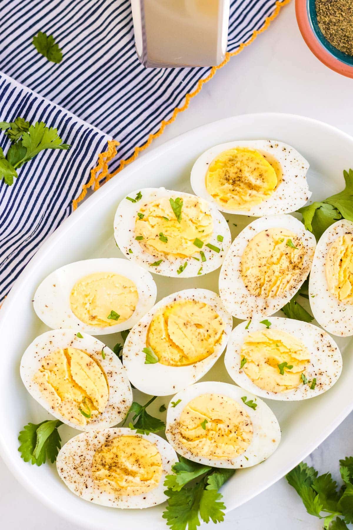 white platter with sliced hard boiled eggs, parsley, blue towel, air fryer