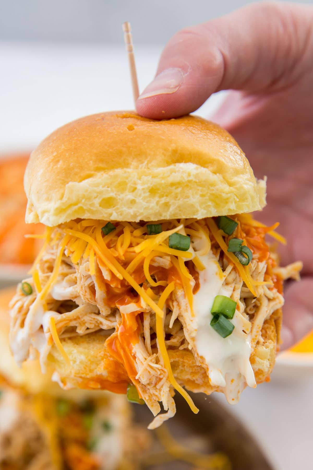 hand holding a buffalo chicken slider with a toothpick