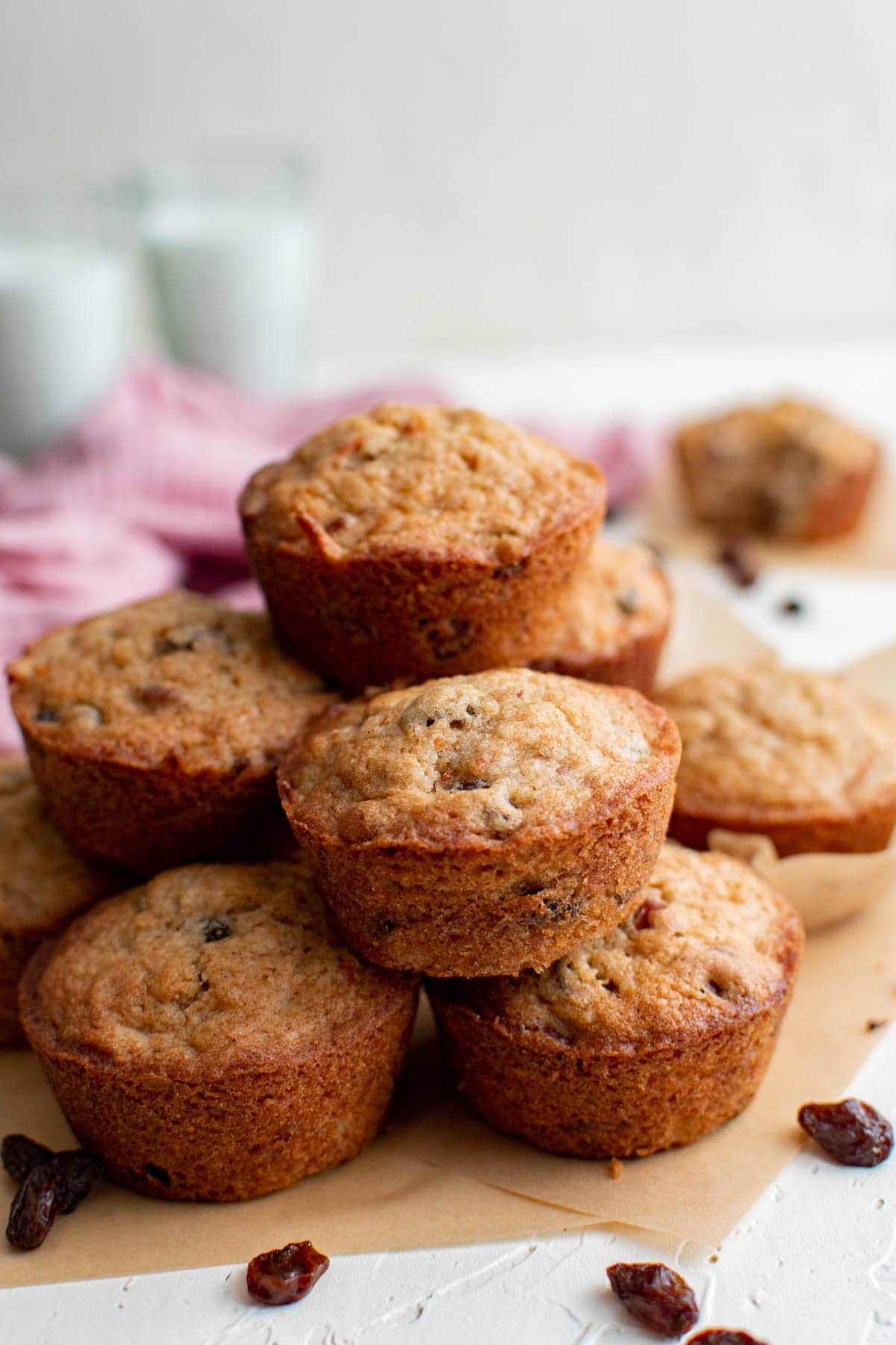 carrot cake muffins stacked on top of one another, parchment paper, raisins