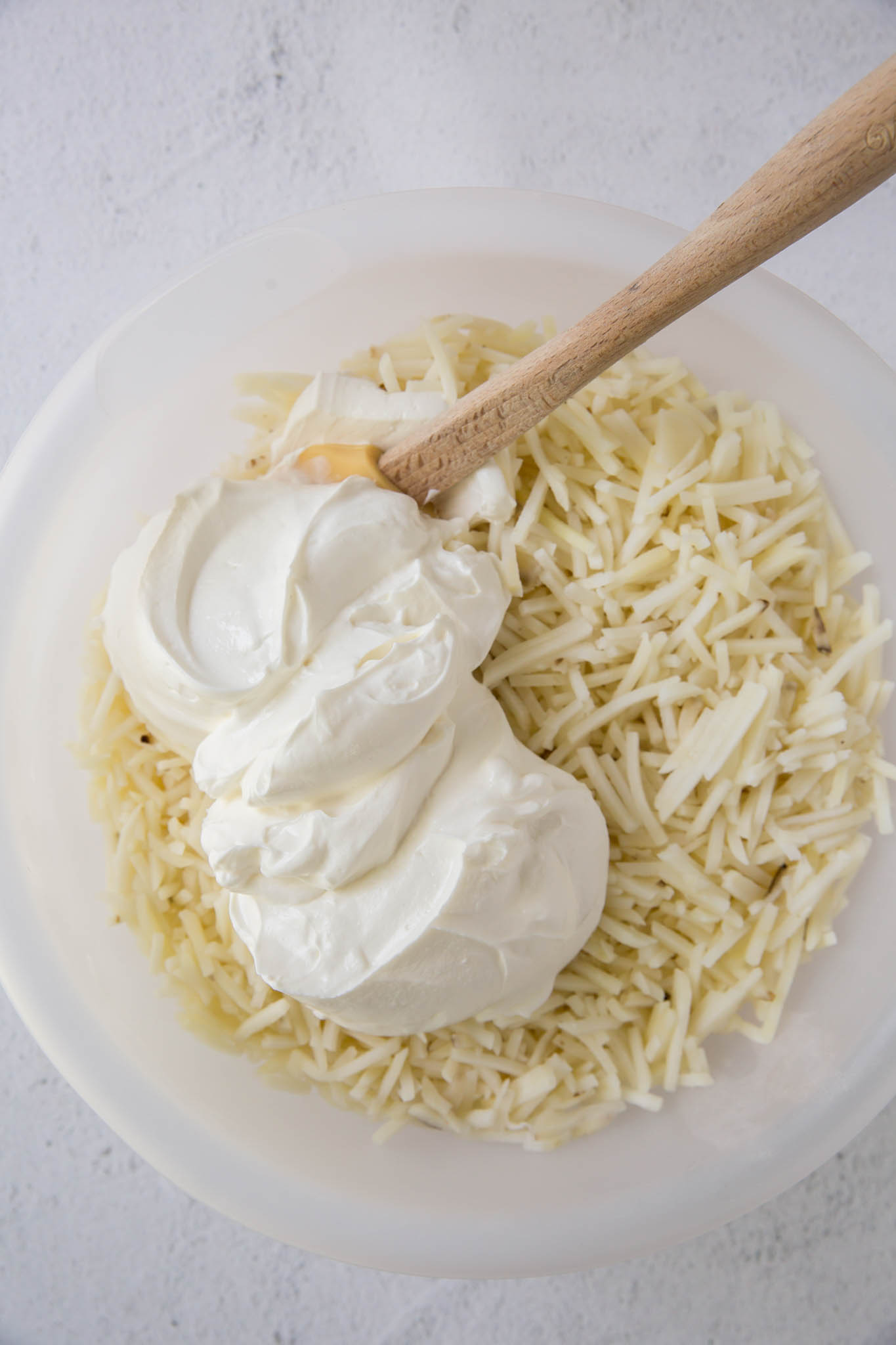 shredded potatoes and sour cream, large bowl, wood spoon