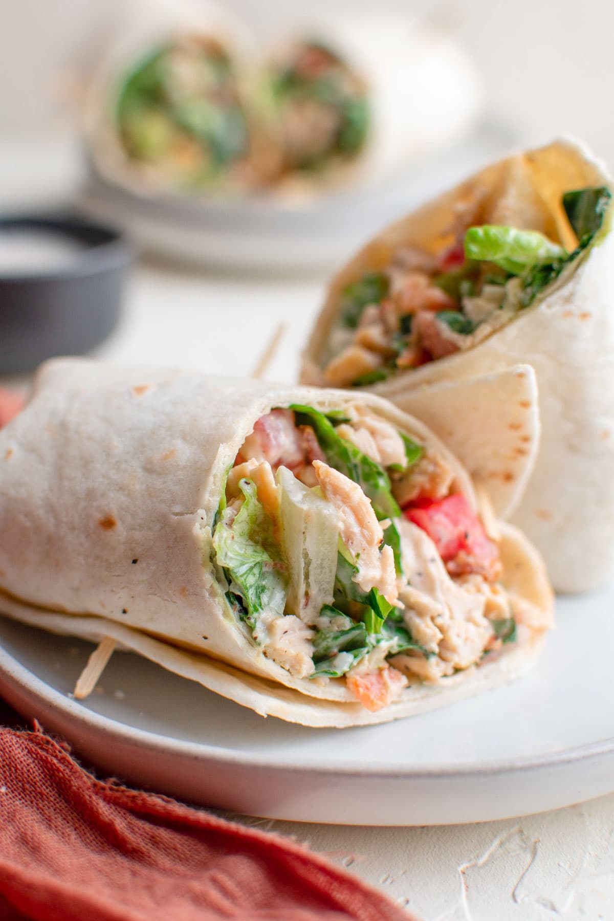 white plates, pink napkin, chicken wraps with lettuce and tomatoes, toothpicks