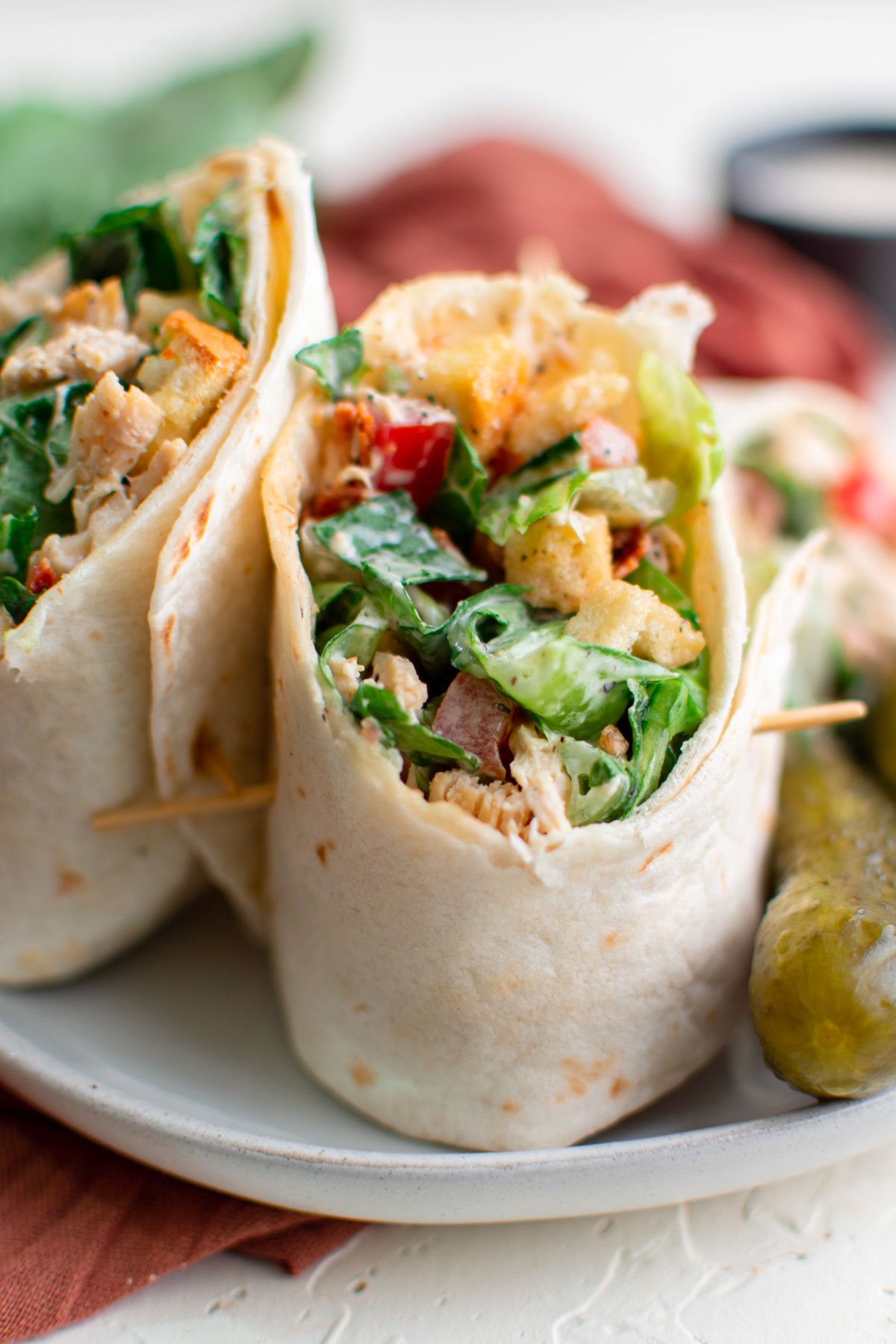 chicken wraps standing on a plate with toothpicks, pink napkin, white plates