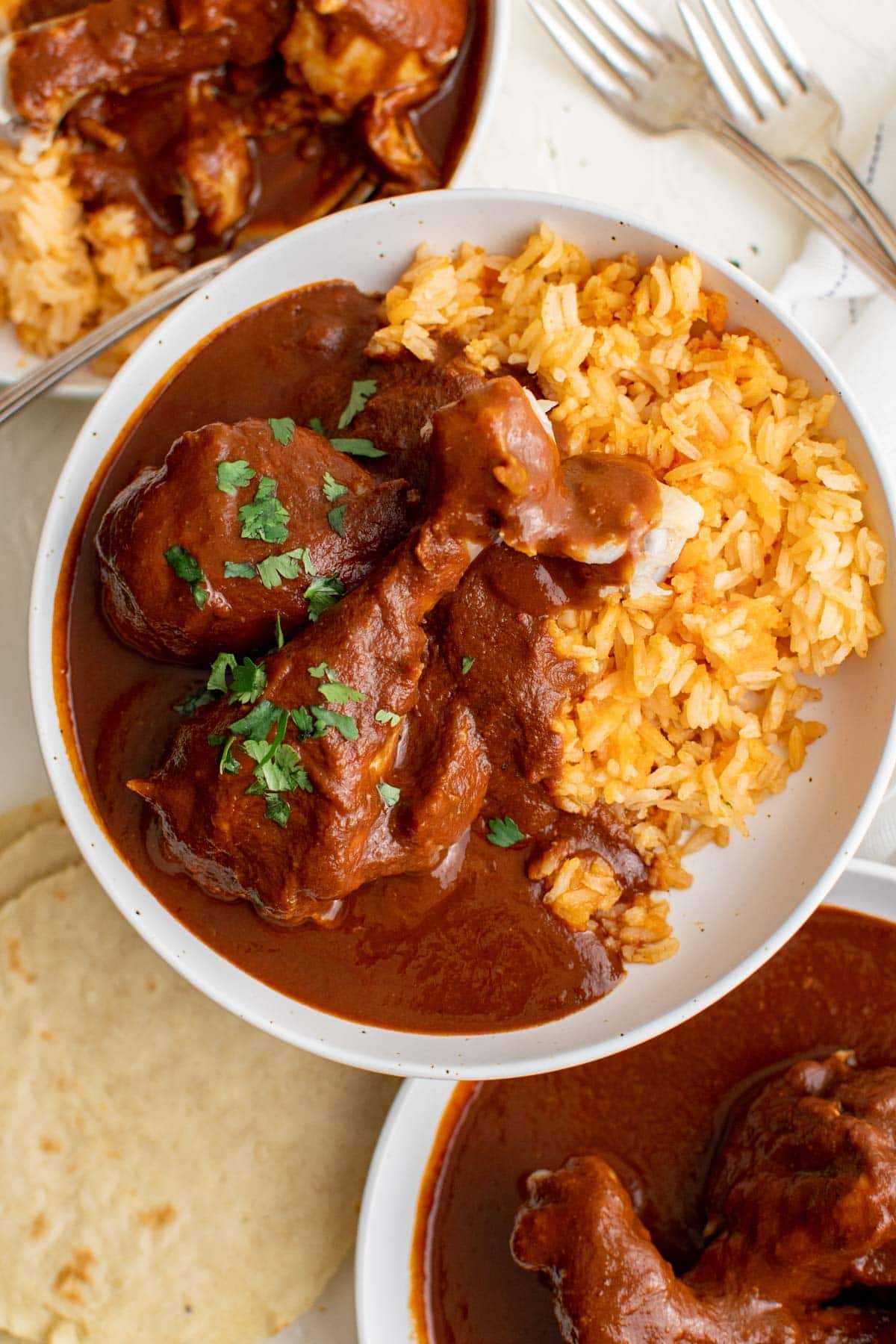 white plate, chicken with mole sauce, mexican rice, forks